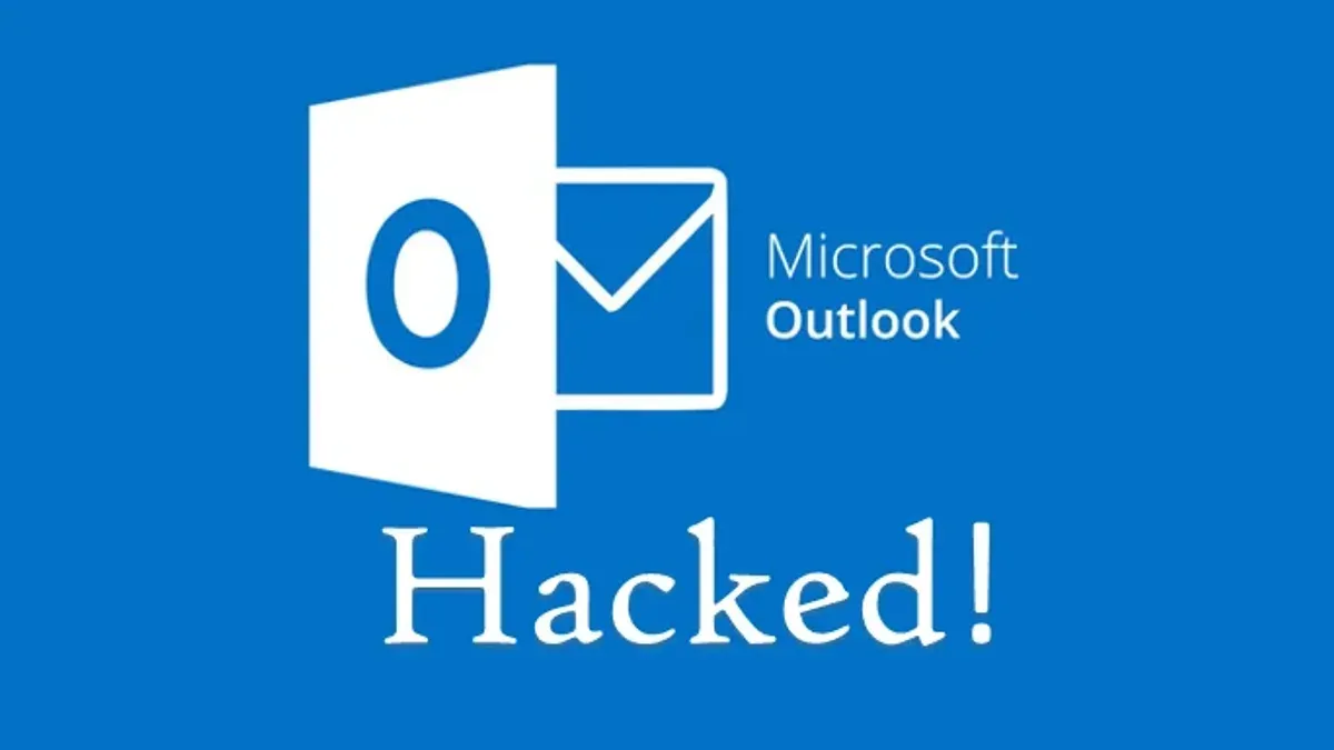 User recovering a hacked Outlook account on laptop with security warning visible